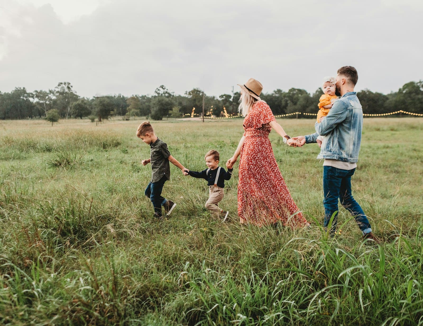 A family walking hand in hand through a grassy field