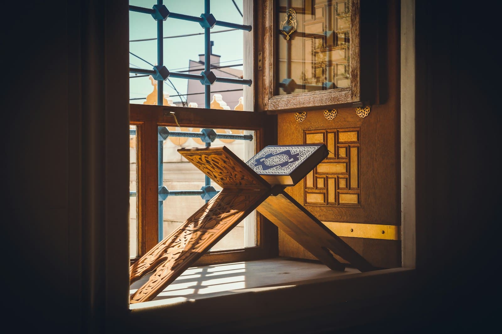 An open book on a wooden stand by a sunlit window
