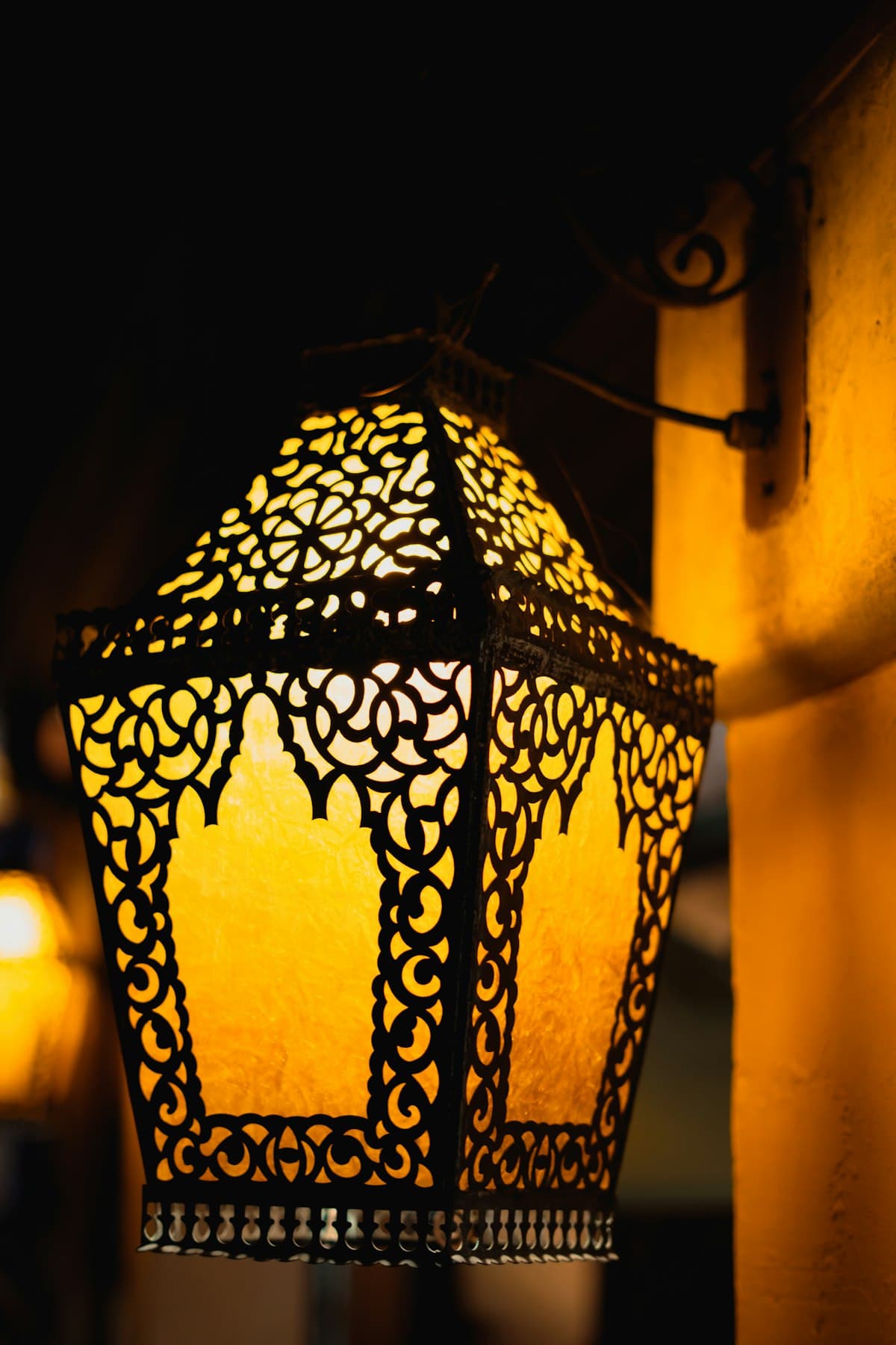 An ornate lantern glowing on a dark wall