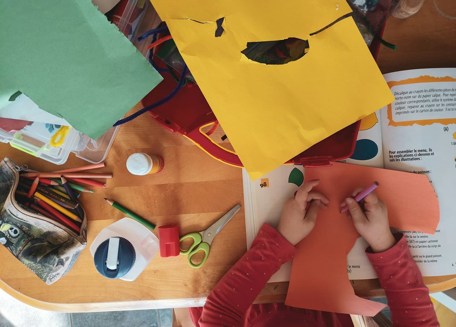 Children cutting and gluing colorful paper at a craft table