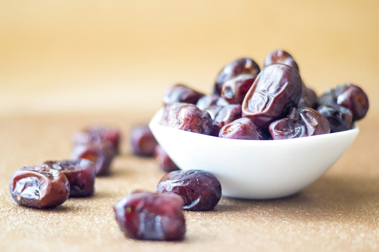 A white bowl of dates on a table